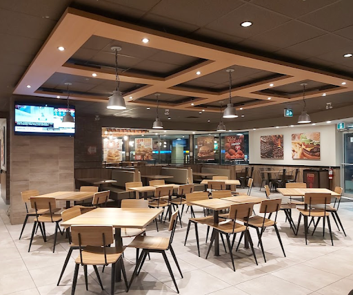 A restaurant with tables and chairs and a tv on the wall.