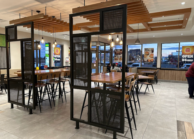 A restaurant with tables and chairs and a divider between the tables.