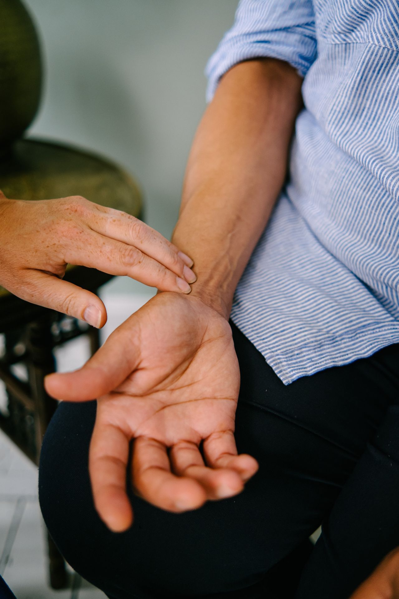 A close-up of an acupuncturist reading a patient's pulse who is lying down. It's a key diagnostic pillars of acupuncture.