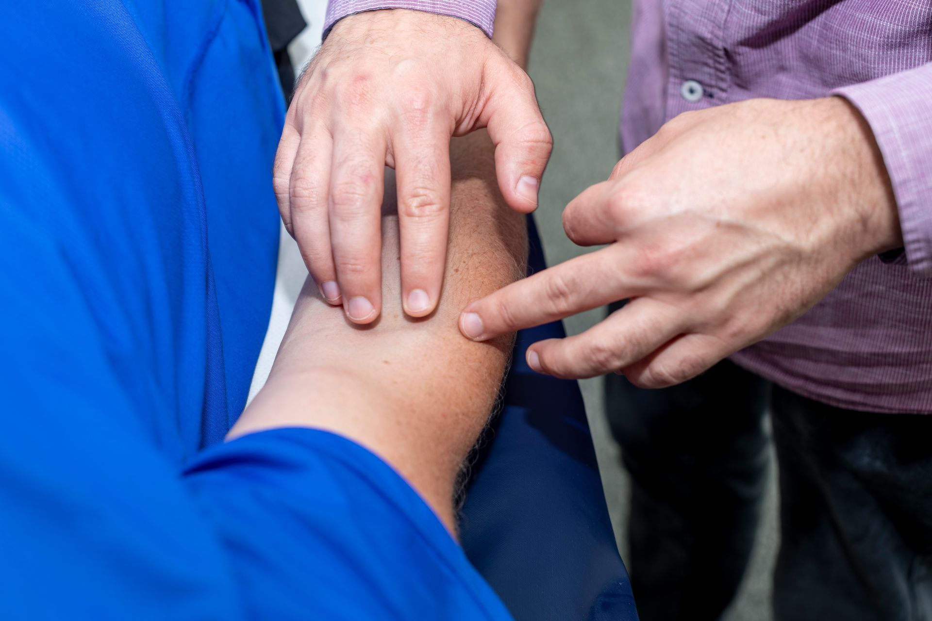 A close-up of an acupuncturist palpating a patient's elbow whilst finding an acupuncture point called Large Intestine 11.