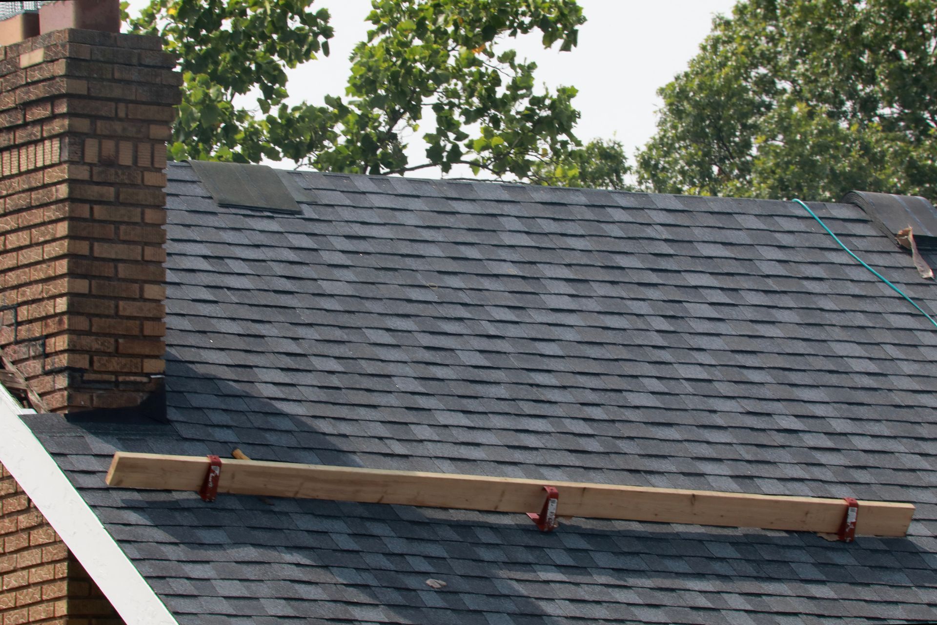 A roof with a chimney and a piece of wood on it