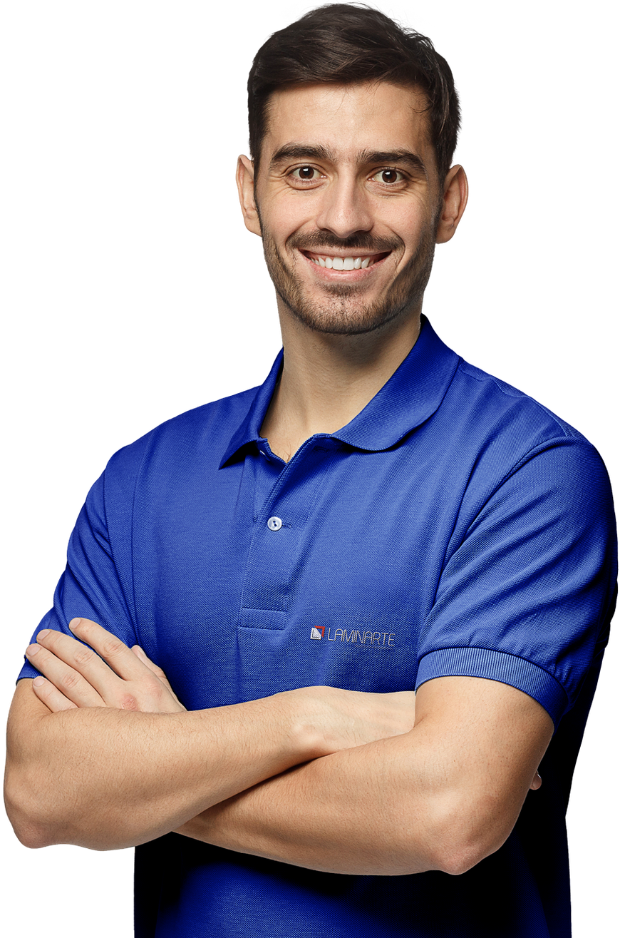 Um homem de camisa polo azul está sorrindo com os braços cruzados.