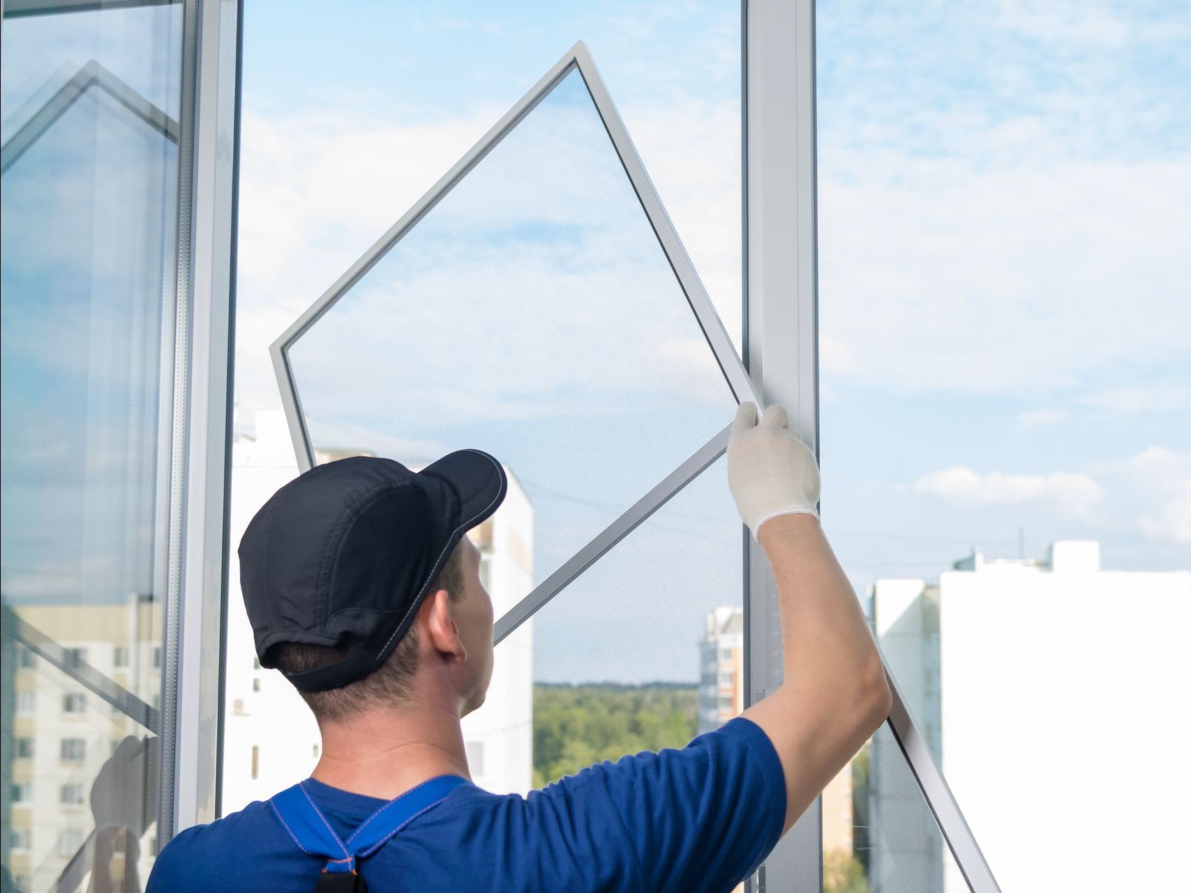 Um homem está instalando uma tela em uma janela.