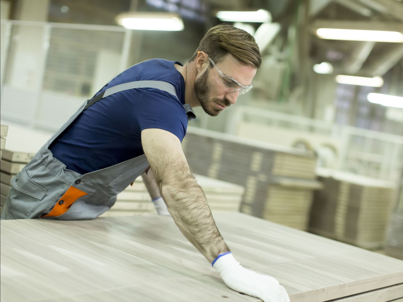 Um homem está trabalhando em um pedaço de madeira em uma fábrica.