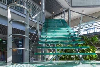 Uma escada de vidro com corrimão de metal em um prédio