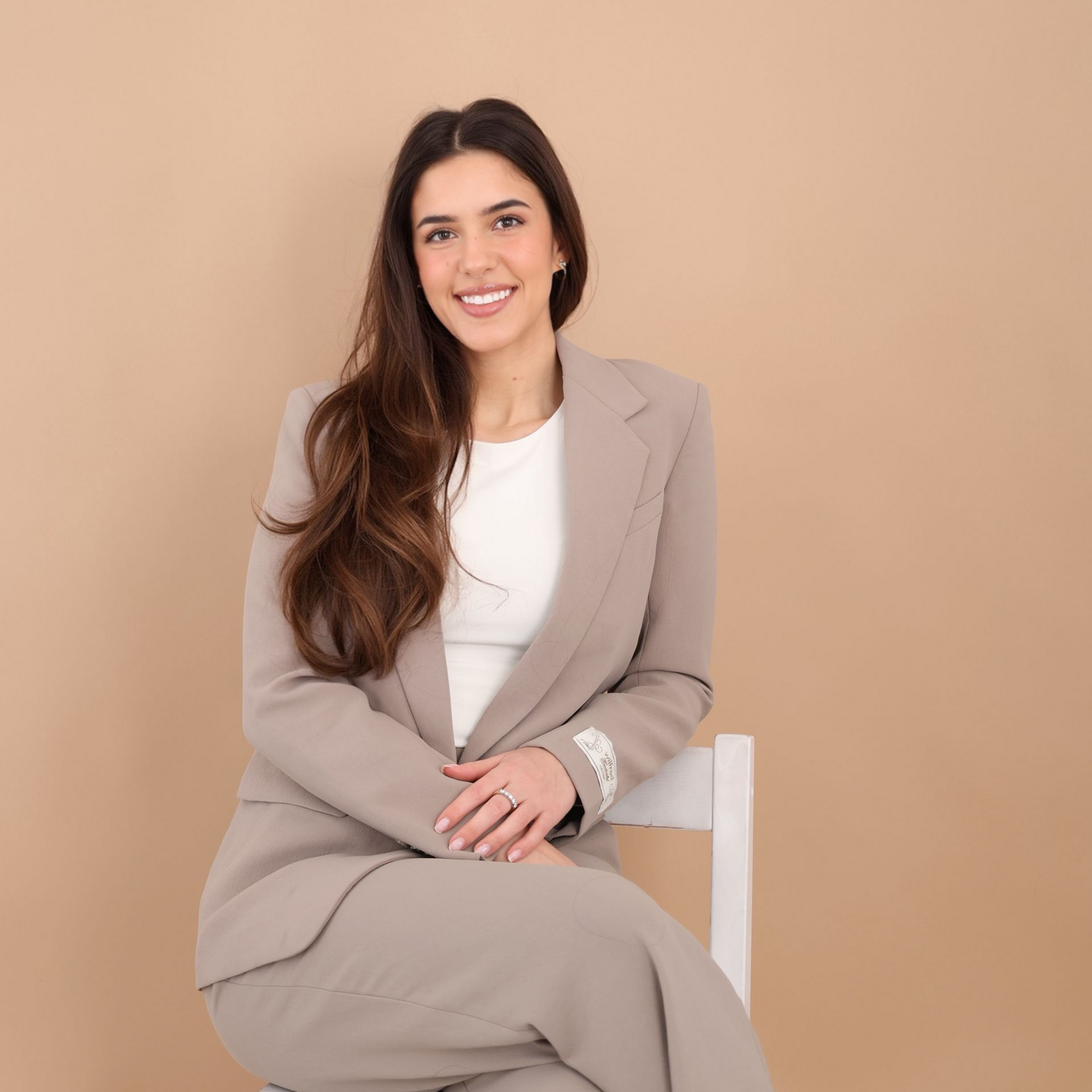 Emma Bannister headshot sitting on white chair