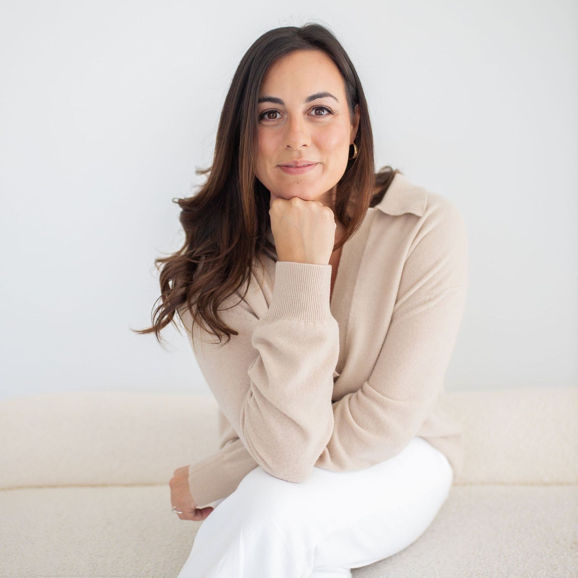 Nicole Presutti headshot sitting on white couch