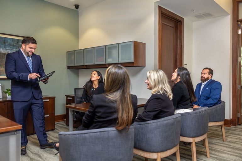 Man in suit presenting to group in office setting.