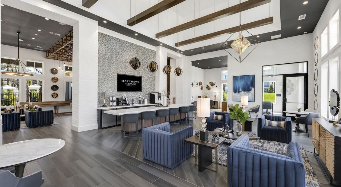 Lounge area with blue couches, a bar, and decorative ceiling beams.