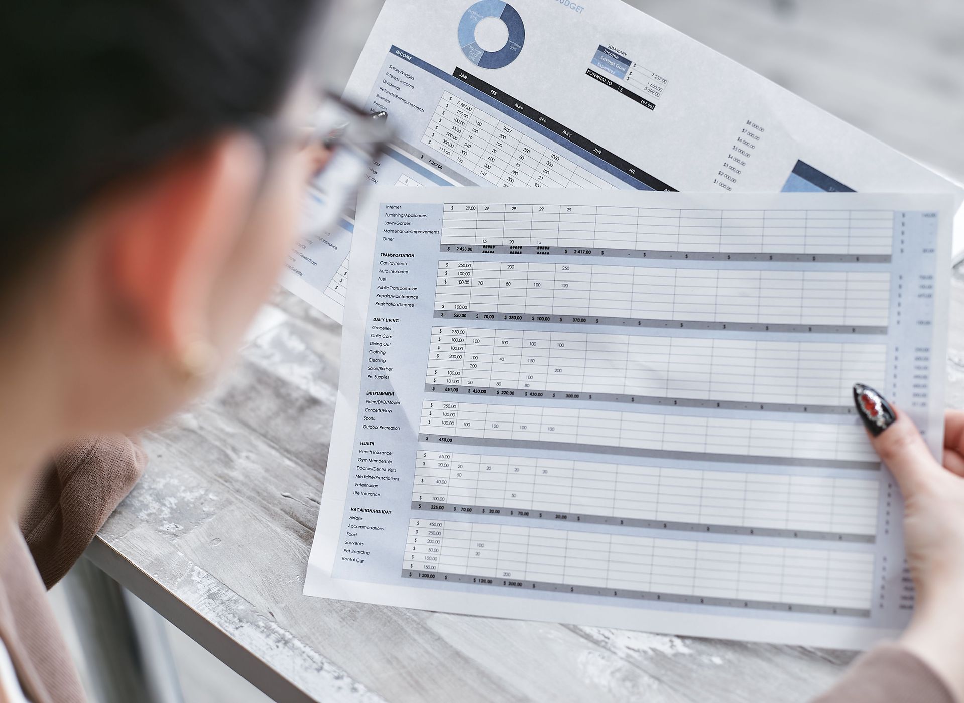 Person reviewing a printed form and calculator on a desk, with papers and a pen nearby.