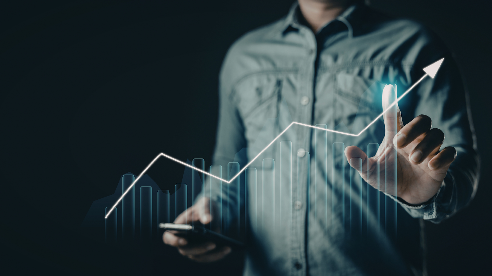 A person in a gray shirt interacts with a glowing, upward-trending digital chart against a dark background.