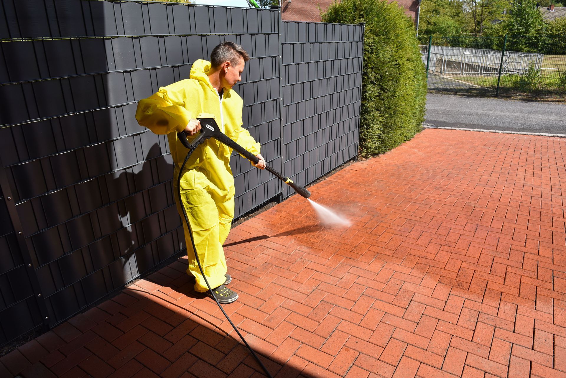 A brick wall is being cleaned with a high pressure washer.