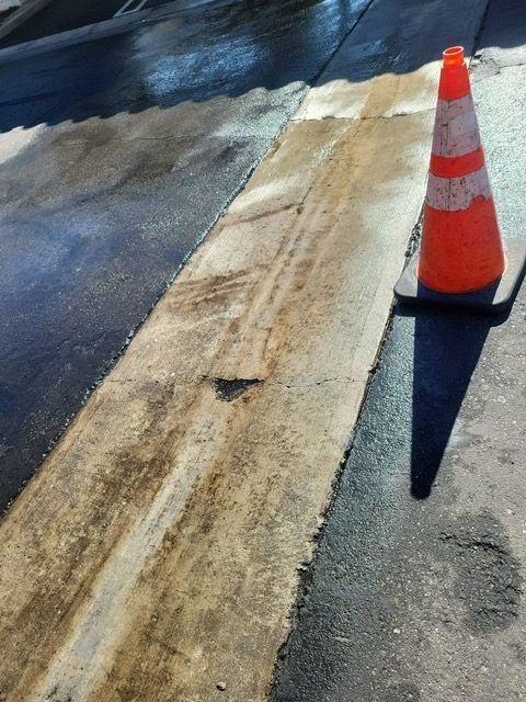 An orange and white traffic cone sits on the side of a road