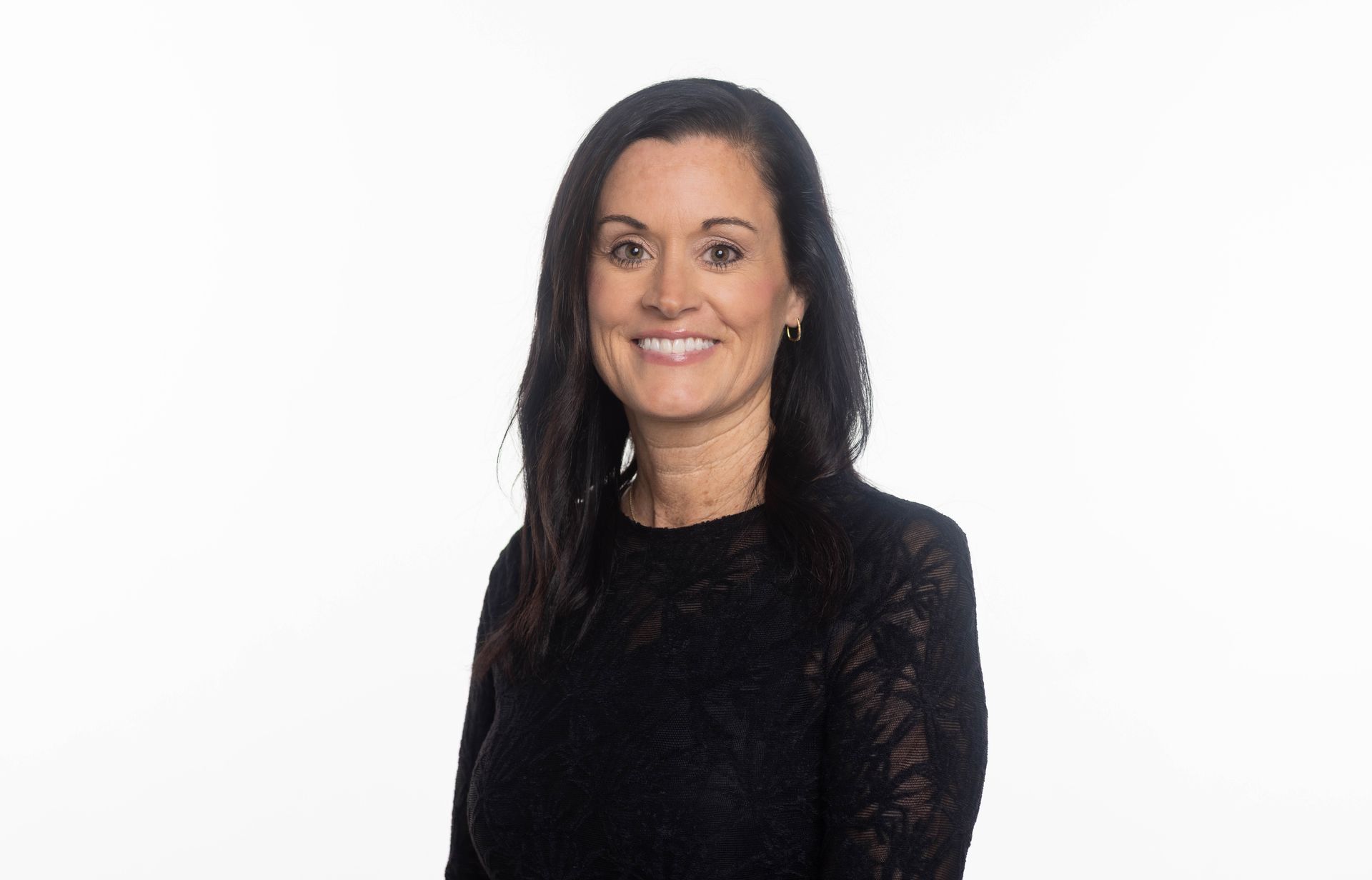 A woman is sitting on a pile of rocks and smiling.