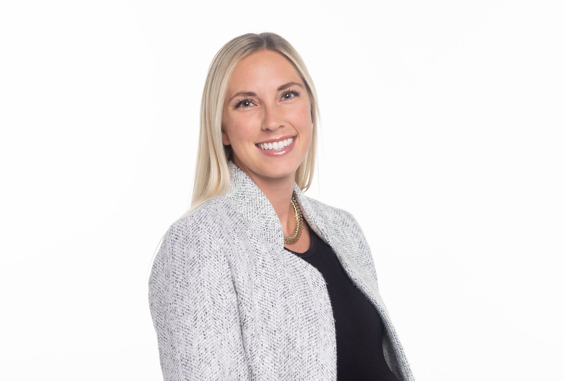 A woman in a black dress is standing in front of a stone wall.
