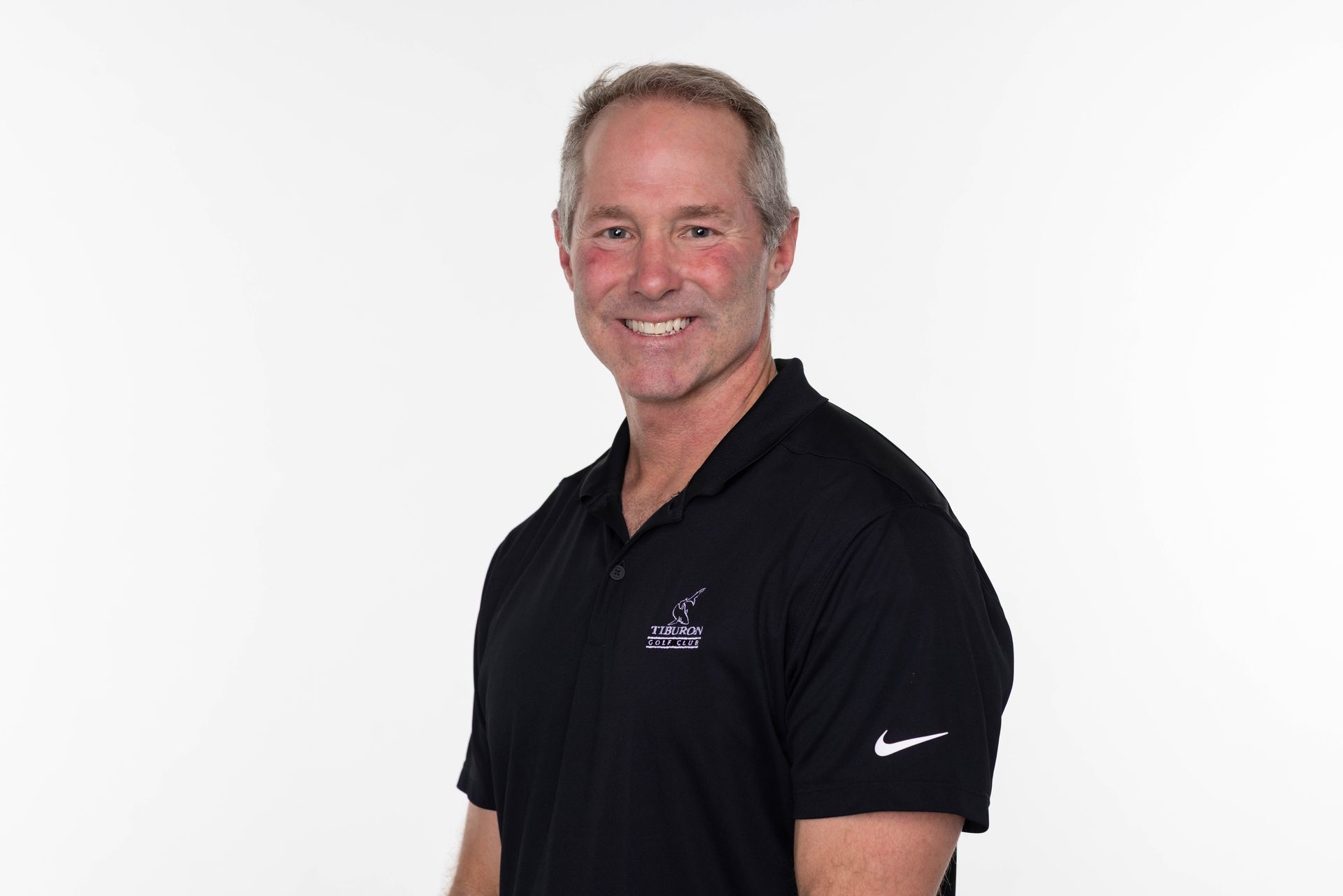 A man in a blue jacket and plaid shirt is smiling for the camera.