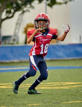 A young boy wearing a football uniform with the number 18 on it