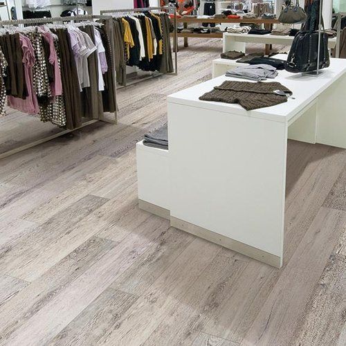 A clothing store with a wooden floor and clothes hanging on racks.