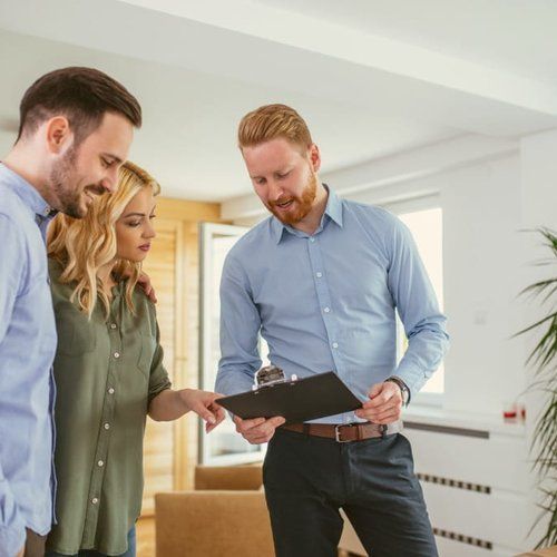 A man and a woman are looking at a clipboard in a living room.