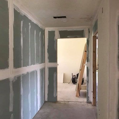 A hallway with drywall walls and a wooden ladder.