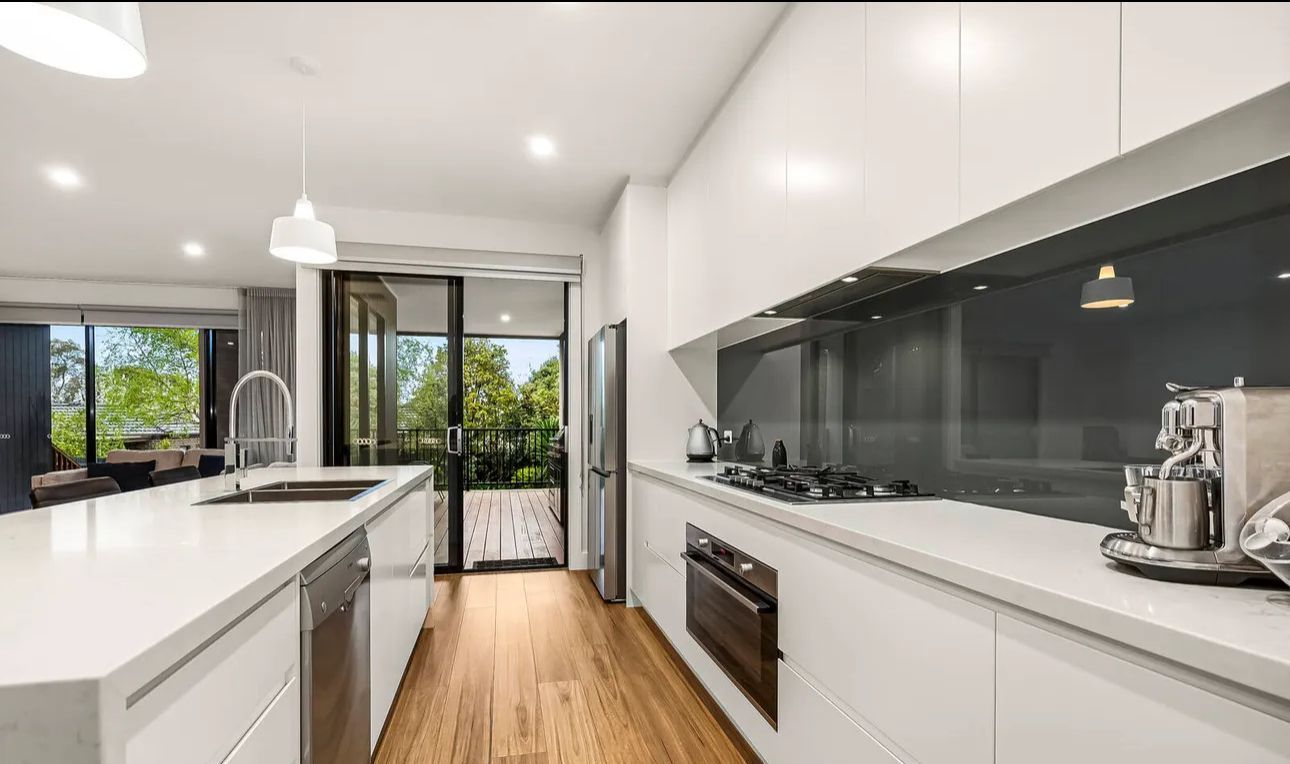 A kitchen with white cabinets , stainless steel appliances and a large island.