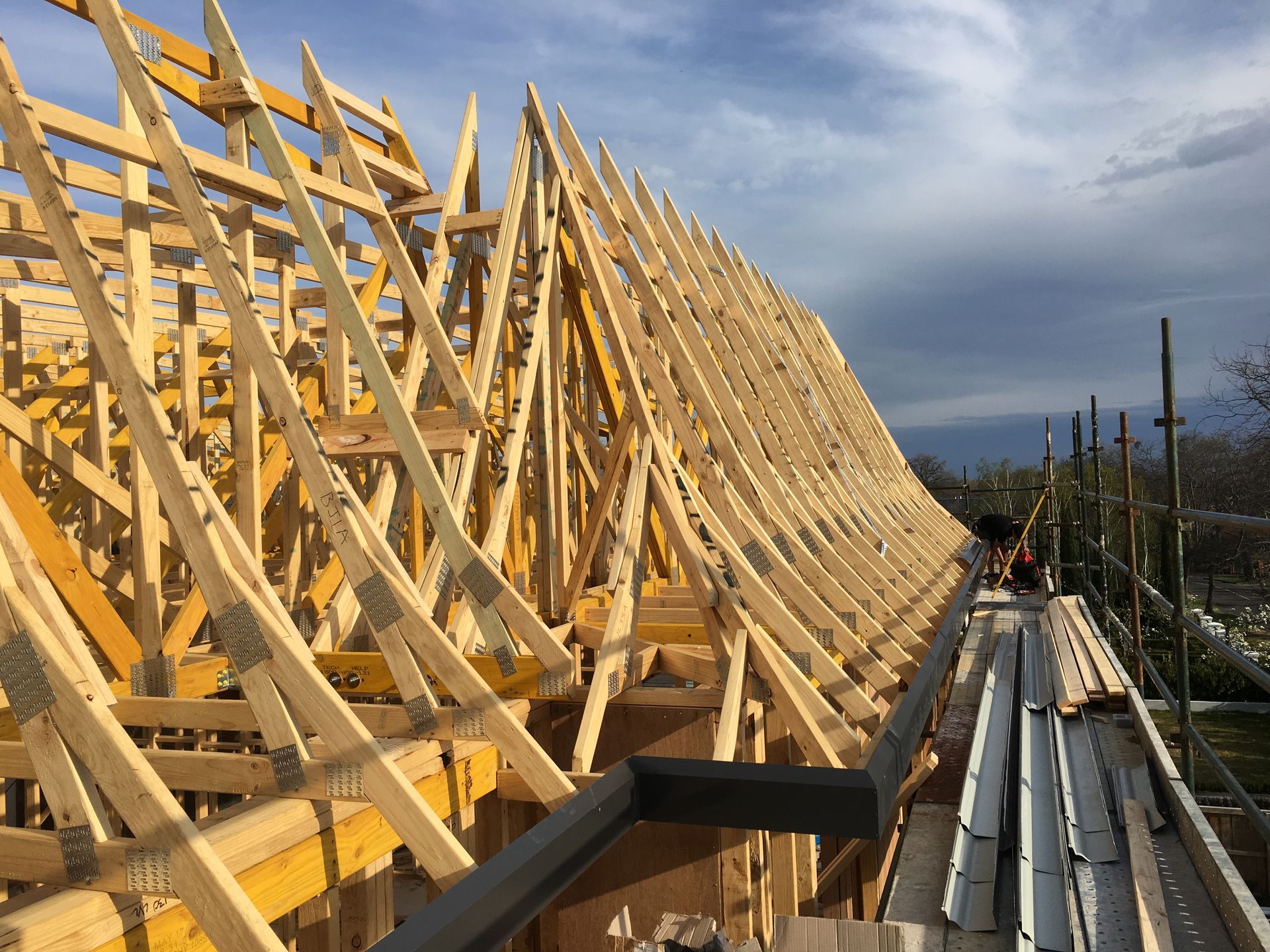 A large wooden structure is being built with a blue sky in the background.
