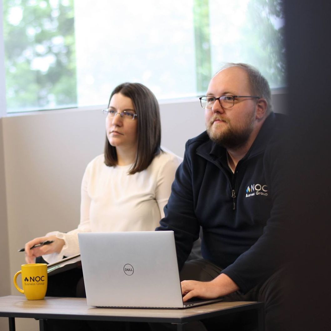 A man and a woman sit in front of a dell laptop