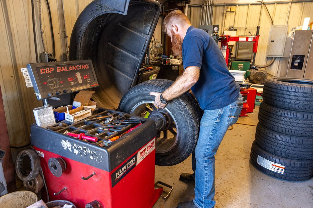 Mechanic balancing a tire on a machine in a garage.