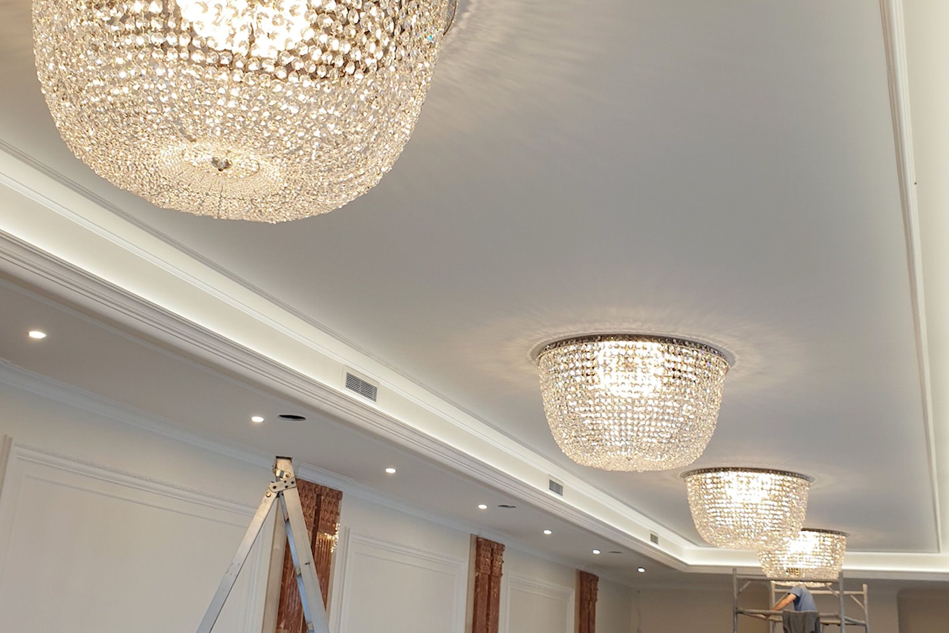 Layered LED lighting and chandeliers in a residential hall – custom lighting upgrade by Astero Electrical
