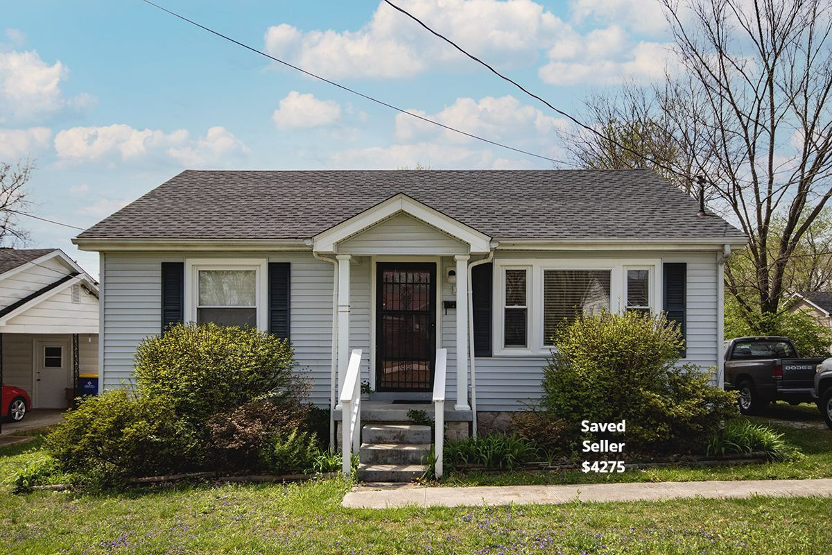 Small gray house with dark roof, porch, shrubs. Saved Seller $4275.