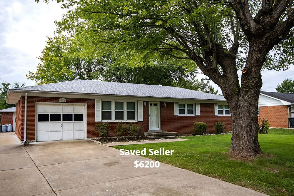 Brick ranch house with a garage and a large tree in the front yard.