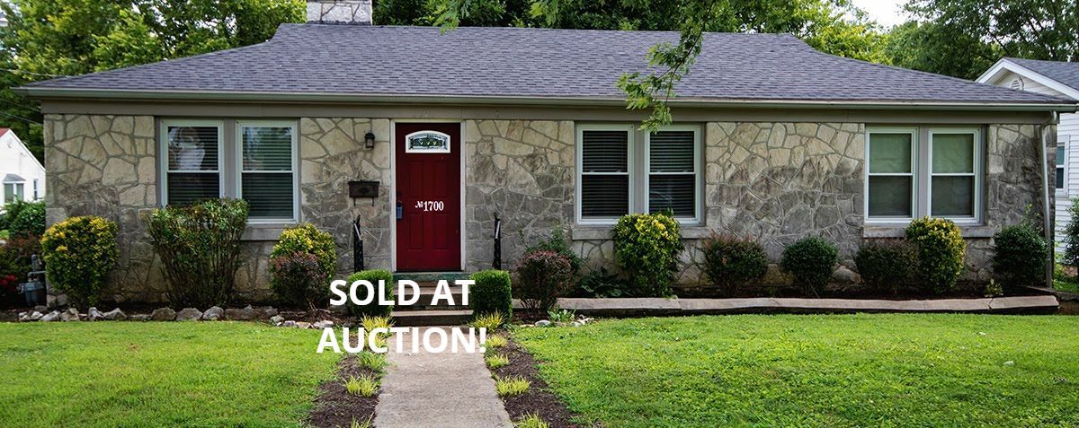 Stone-covered house with a red door, set on a green lawn. Text says