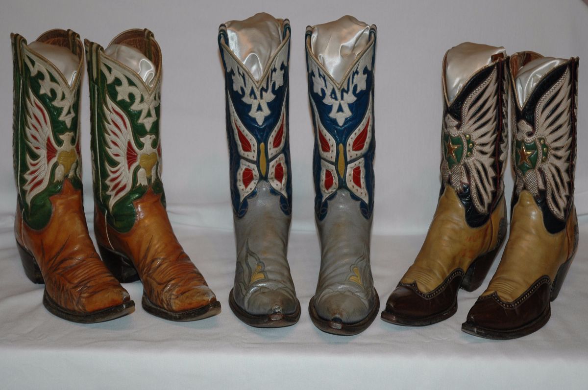 Four pairs of cowboy boots are lined up on a table