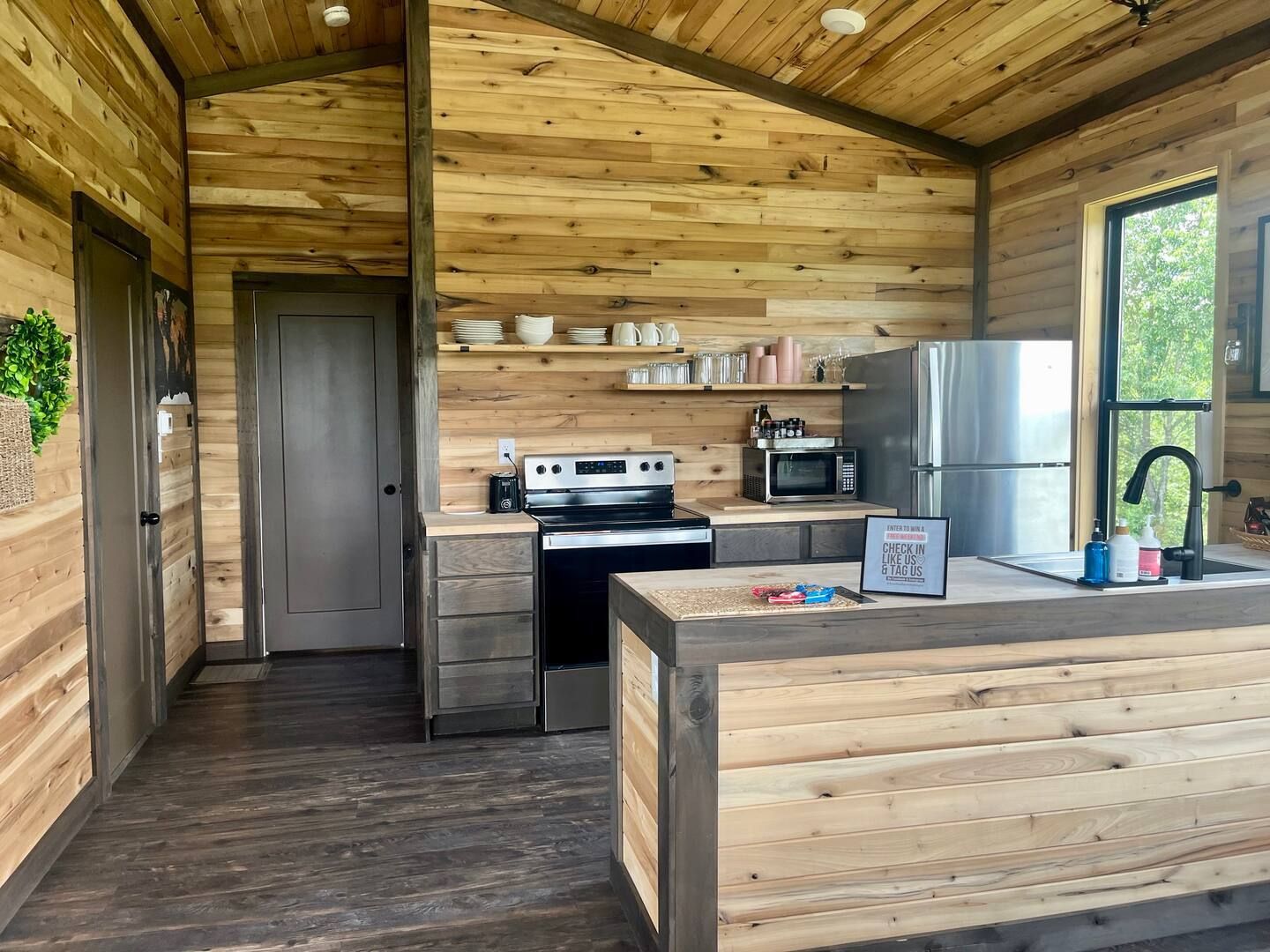 A kitchen with a stove , refrigerator , microwave and sink.