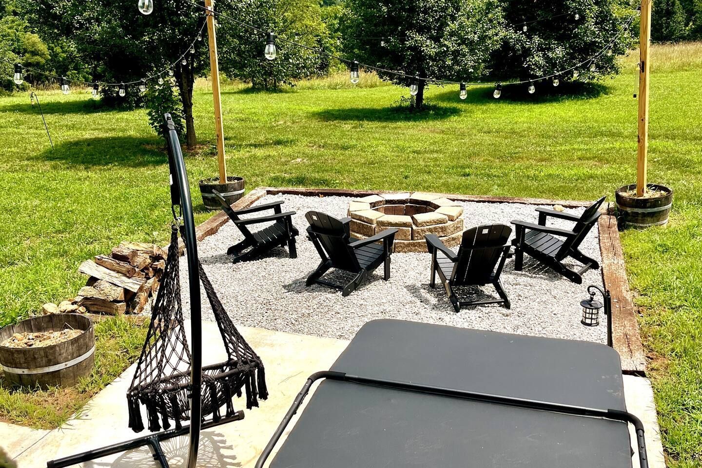 There is a fire pit in the middle of the yard with chairs around it.