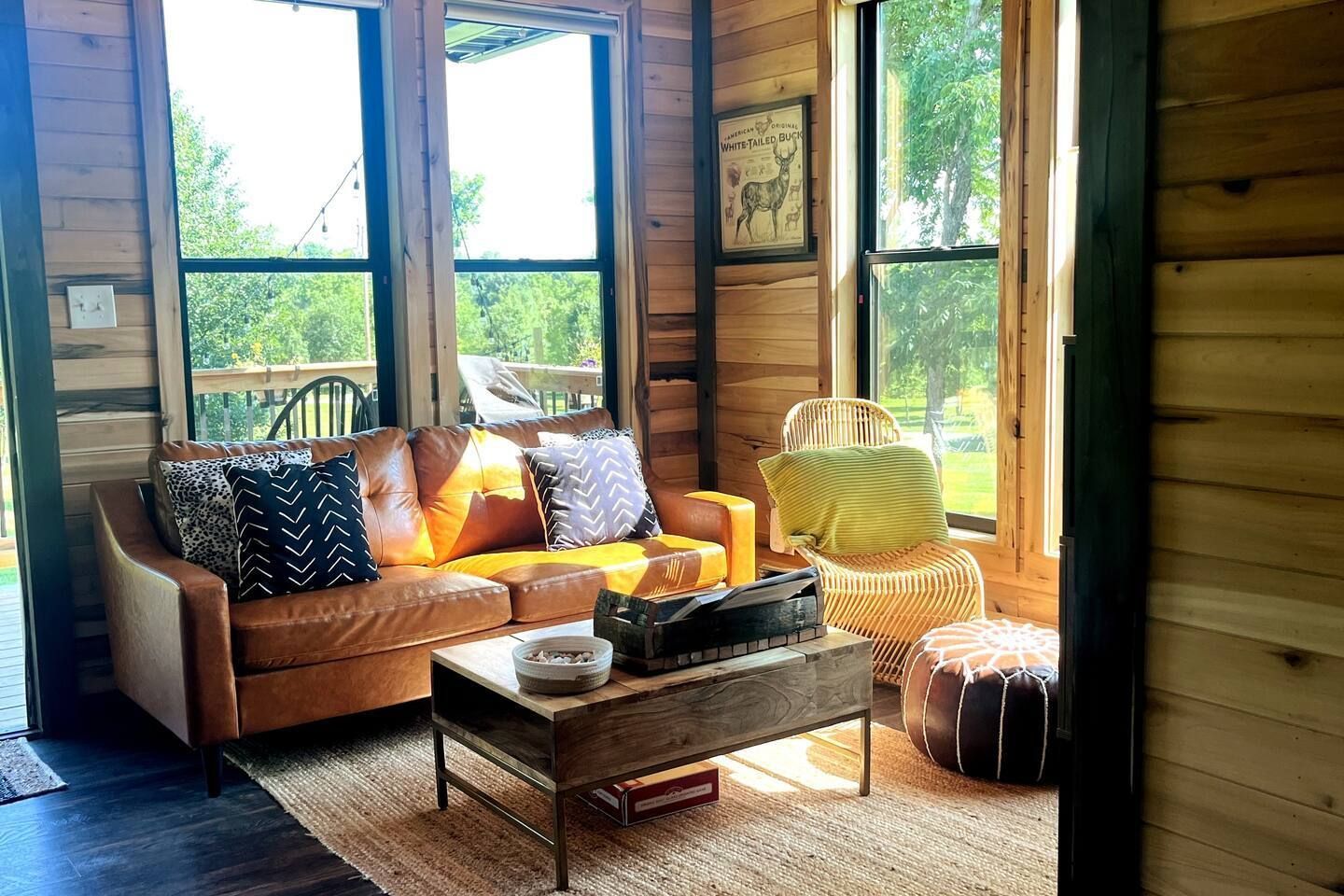 A living room in a log cabin with a couch , coffee table and chairs.