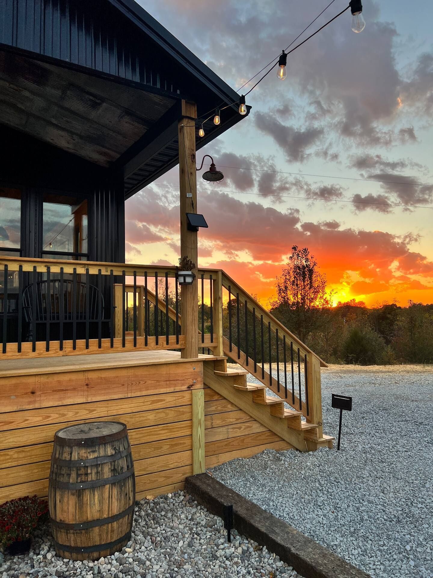 A house with a wooden deck and stairs with a sunset in the background.