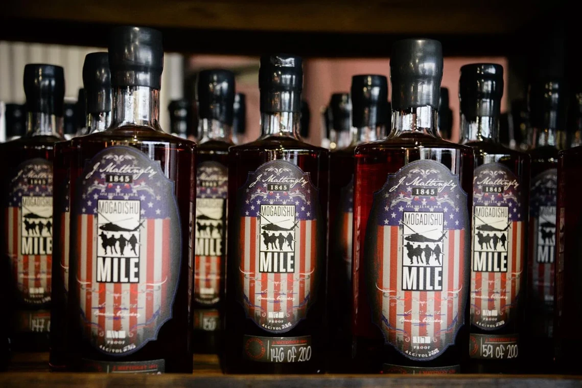 A row of bottles of whiskey are lined up on a shelf.