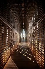 A long wooden hallway with a window at the end of it.