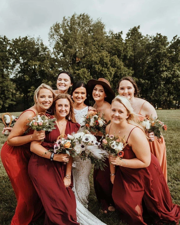 A bride and her bridesmaids are posing for a picture in a field.