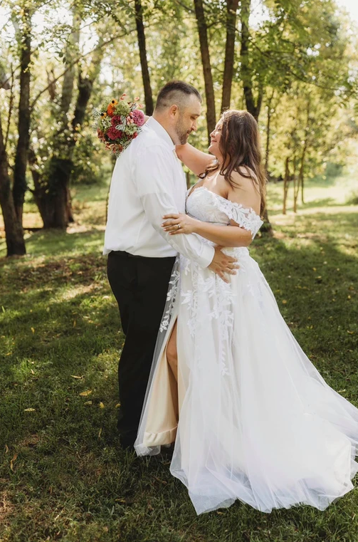 A bride and groom are posing for a picture in the grass.