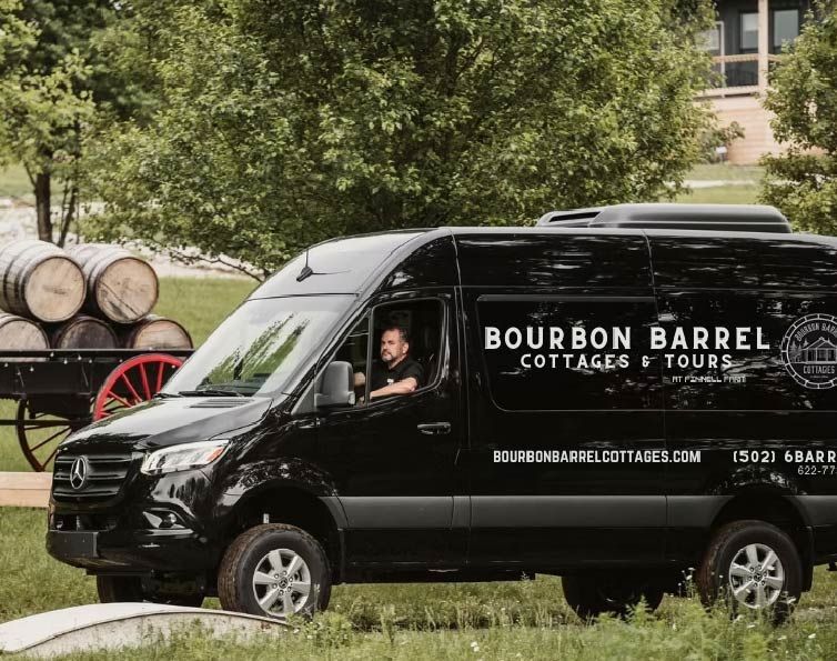 A man is driving a bourbon barrel cottages and tours van.