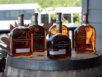 Four bottles of whiskey are sitting on top of a wooden barrel.