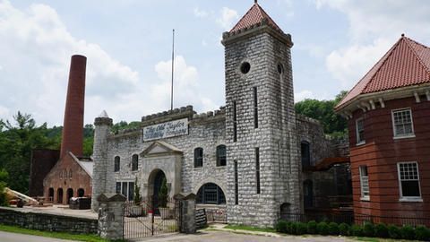 A large brick building with a tower and a chimney in the background.