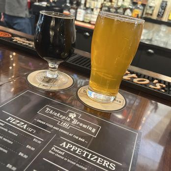 Two glasses of beer are sitting on a bar next to a menu.