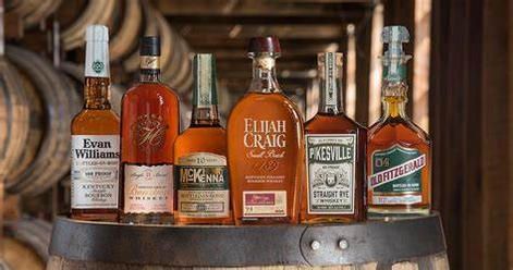 A group of bottles of whiskey are sitting on top of a wooden barrel.