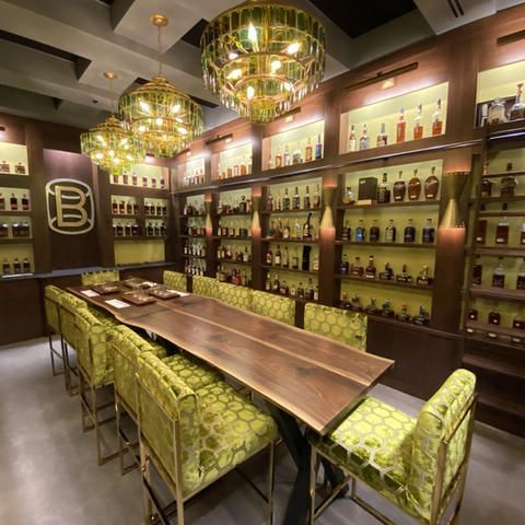 A dining room with lots of bottles on shelves and a large b on the wall
