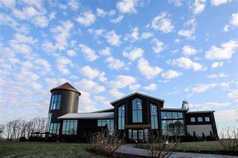 A large house with a silo in the background and a blue sky with clouds.