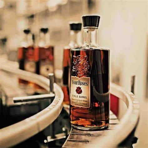 A bottle of four roses whiskey is sitting on a conveyor belt.