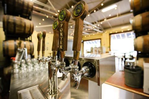 A bar with a lot of beer taps and barrels in the background.